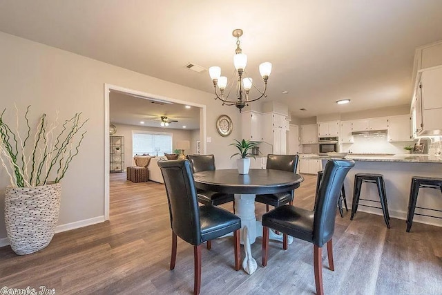 dining space featuring dark wood-type flooring and ceiling fan with notable chandelier