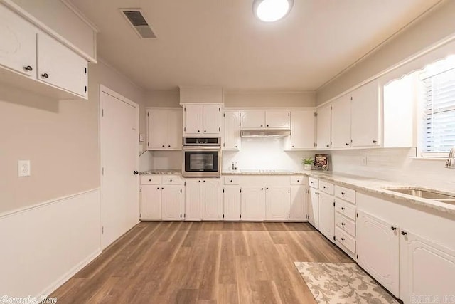 kitchen featuring oven, white cabinetry, cooktop, light wood-type flooring, and sink