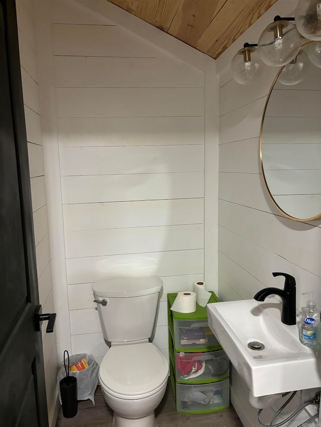 bathroom with wood ceiling, wood walls, sink, and toilet