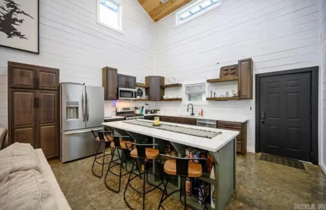 kitchen featuring light countertops, open shelves, a kitchen breakfast bar, and appliances with stainless steel finishes