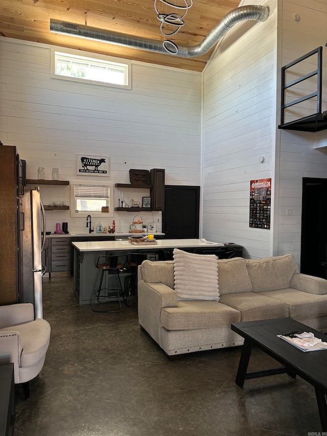 living room with wooden walls, a towering ceiling, and wooden ceiling