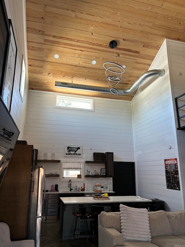 kitchen with wooden ceiling, sink, wooden walls, and a kitchen breakfast bar