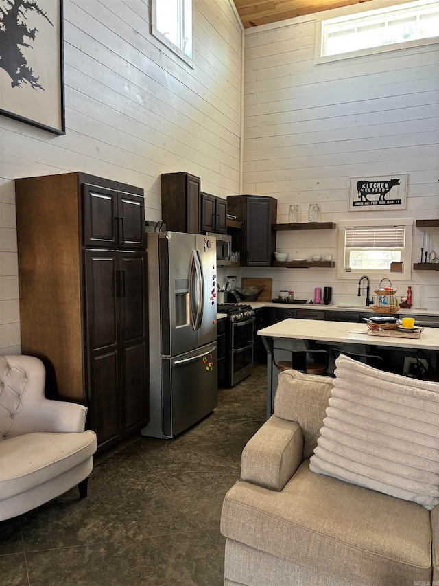 kitchen featuring a wealth of natural light, wooden walls, and appliances with stainless steel finishes