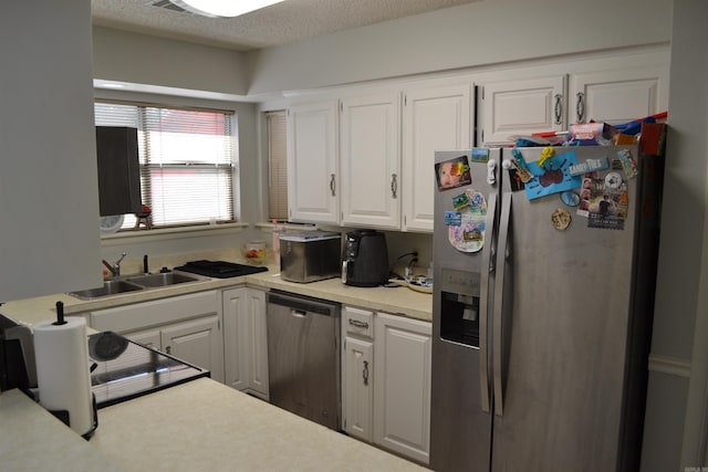 kitchen featuring sink, appliances with stainless steel finishes, a textured ceiling, and white cabinetry