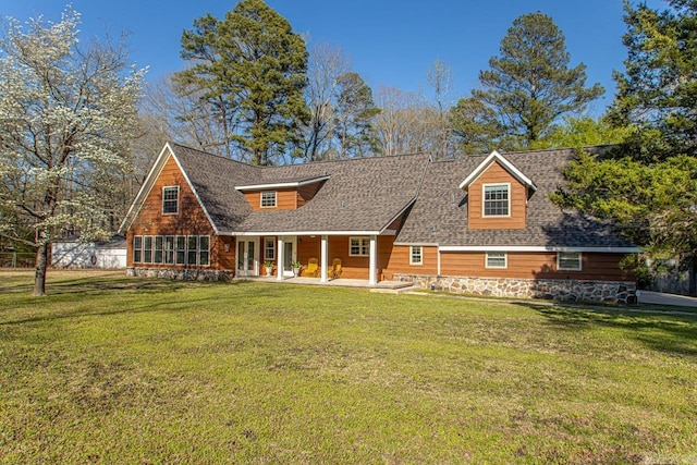 view of front of home with a front lawn, roof with shingles, and stone siding