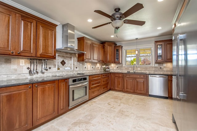 kitchen with appliances with stainless steel finishes, sink, wall chimney exhaust hood, dark stone counters, and ornamental molding