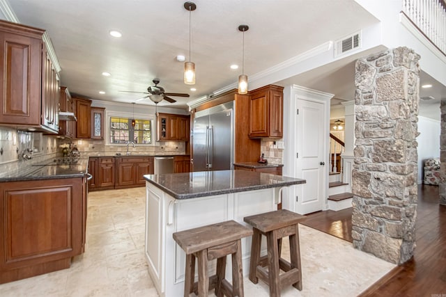 kitchen with a center island, appliances with stainless steel finishes, backsplash, and ceiling fan