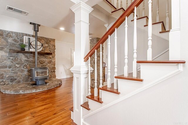 stairs with wood finished floors, visible vents, a wainscoted wall, and a wood stove