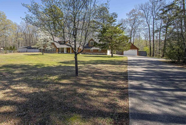 view of front of property featuring a detached garage, driveway, a front yard, and fence