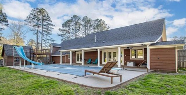 view of pool featuring a fenced backyard, an outbuilding, a patio, a water slide, and ceiling fan