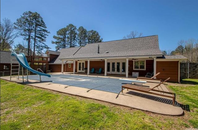 back of property featuring a yard, a patio area, a playground, and a covered pool