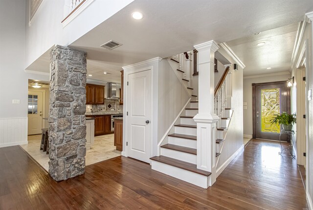 interior space with crown molding, stairs, hardwood / wood-style floors, visible vents, and decorative columns