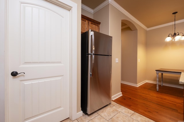 kitchen featuring hanging light fixtures, crown molding, an inviting chandelier, light hardwood / wood-style floors, and stainless steel refrigerator