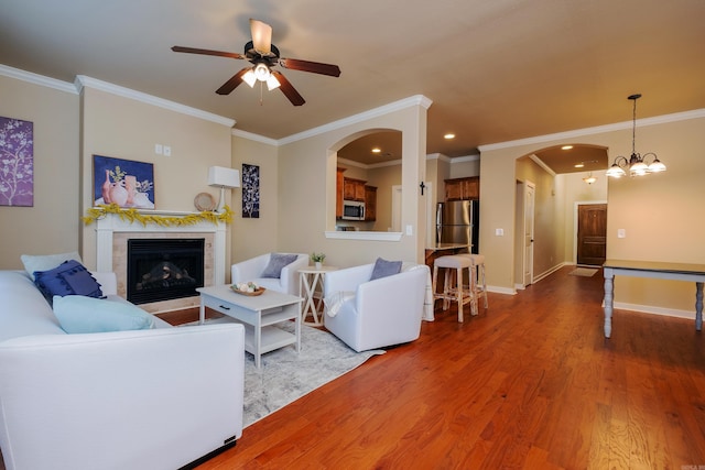 living room with ornamental molding, ceiling fan with notable chandelier, and hardwood / wood-style floors