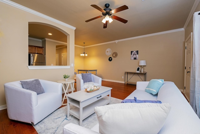 living room with dark wood-type flooring, crown molding, and ceiling fan with notable chandelier