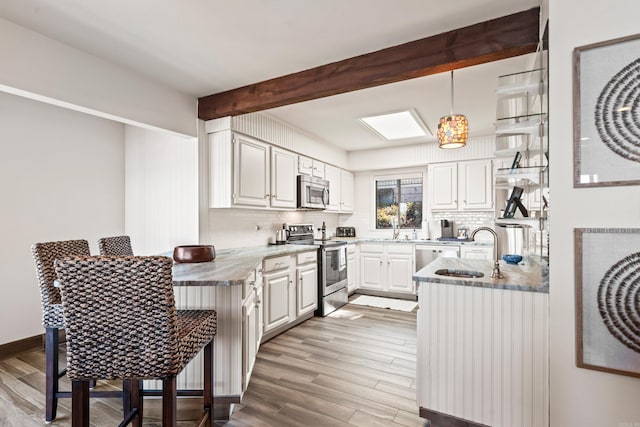 kitchen featuring white cabinets, decorative light fixtures, stainless steel appliances, and kitchen peninsula