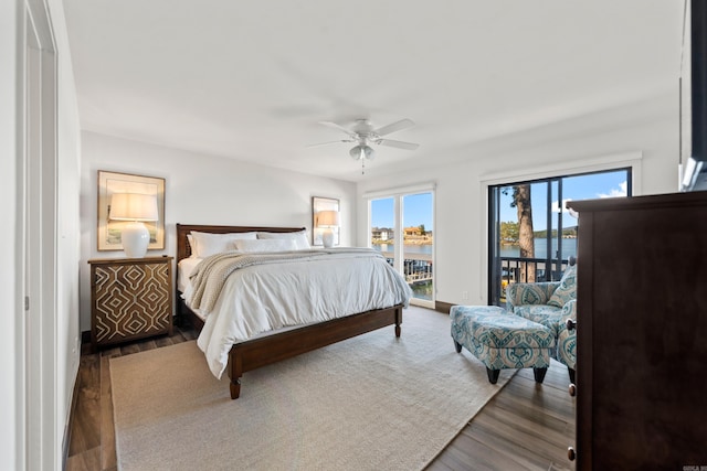 bedroom featuring dark wood-type flooring, ceiling fan, a water view, and access to outside