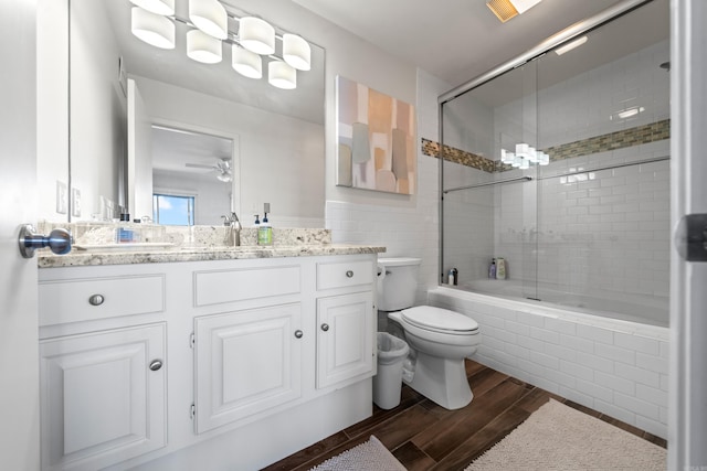 full bathroom featuring enclosed tub / shower combo, ceiling fan, hardwood / wood-style flooring, toilet, and vanity