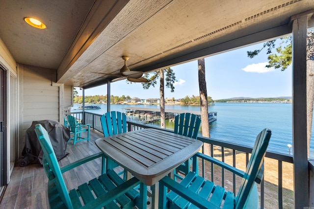 wooden terrace with a water view, ceiling fan, and grilling area