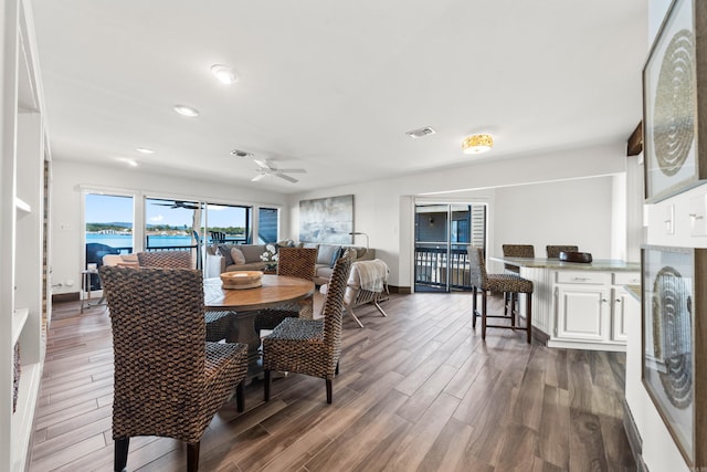 dining space featuring a water view, ceiling fan, and dark hardwood / wood-style floors