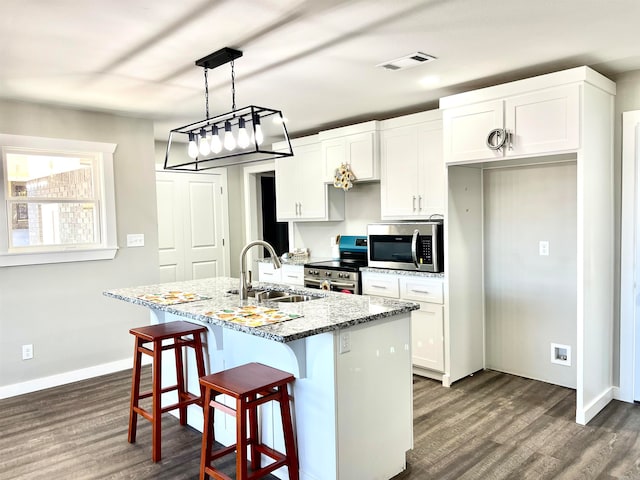 kitchen featuring an island with sink, sink, white cabinets, appliances with stainless steel finishes, and dark hardwood / wood-style flooring