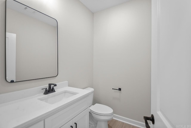 bathroom with vanity, toilet, and hardwood / wood-style flooring