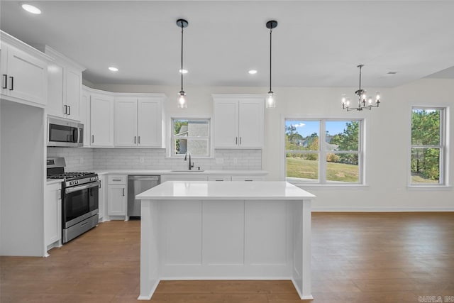 kitchen featuring sink, appliances with stainless steel finishes, hanging light fixtures, and white cabinets