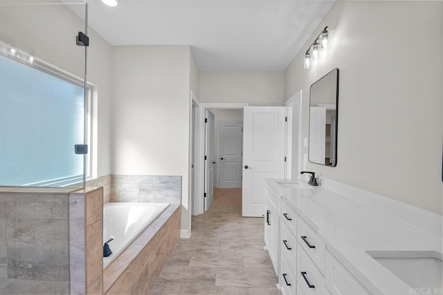 bathroom with vanity and tiled tub