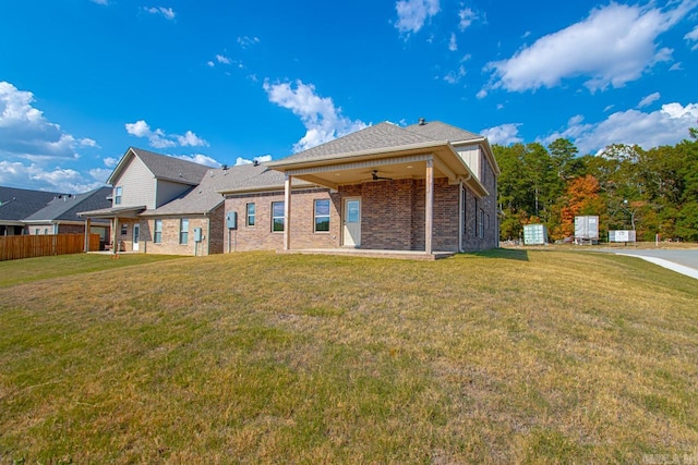 rear view of property with ceiling fan and a lawn