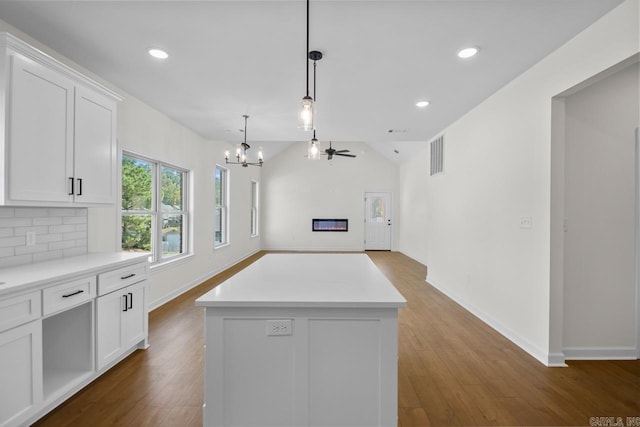 kitchen with ceiling fan with notable chandelier, a center island, white cabinetry, pendant lighting, and hardwood / wood-style flooring