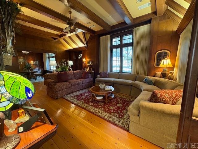 living room featuring wooden walls, vaulted ceiling with beams, wood-type flooring, and ceiling fan