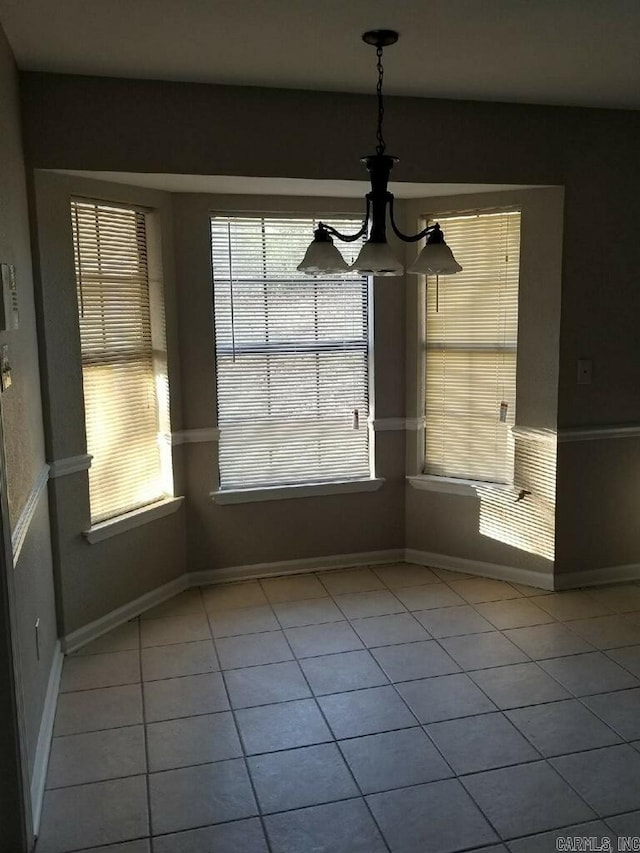 unfurnished dining area with an inviting chandelier, a healthy amount of sunlight, and light tile patterned floors