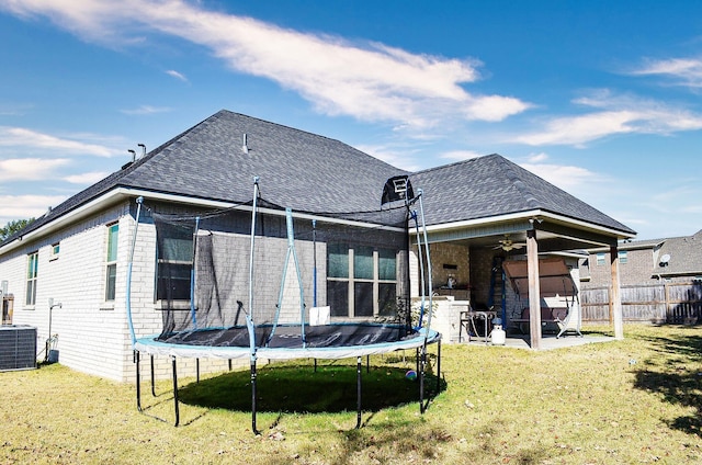 back of property with a patio, central AC, a lawn, and a trampoline