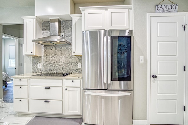 kitchen with wall chimney exhaust hood, white cabinetry, black electric cooktop, and stainless steel refrigerator