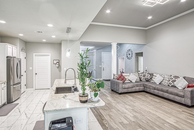 living room with crown molding, sink, light wood-type flooring, and decorative columns