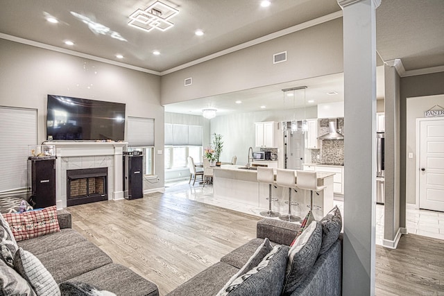 living room featuring ornamental molding, sink, and light hardwood / wood-style floors