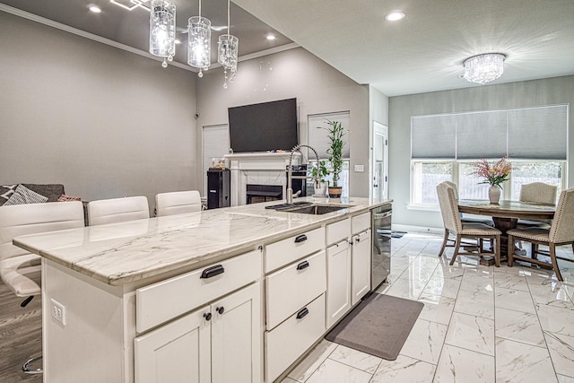 kitchen featuring a center island with sink, a breakfast bar, white cabinetry, decorative light fixtures, and sink