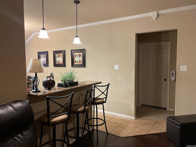 bar with crown molding, hanging light fixtures, and light hardwood / wood-style floors