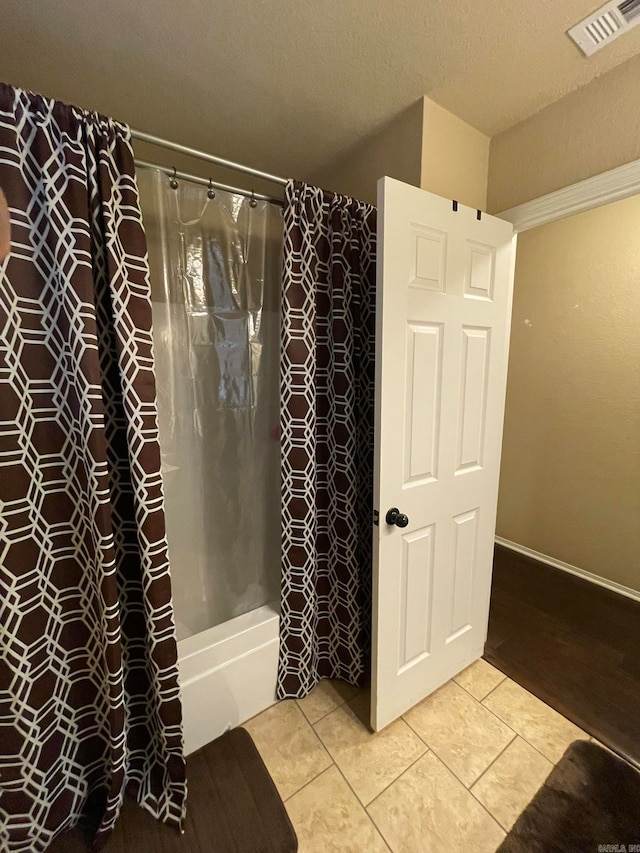 bathroom with tile patterned floors, a textured ceiling, and shower / bathtub combination with curtain