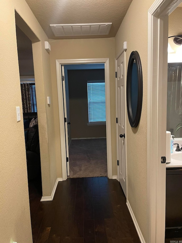 corridor featuring dark wood-type flooring and a textured ceiling