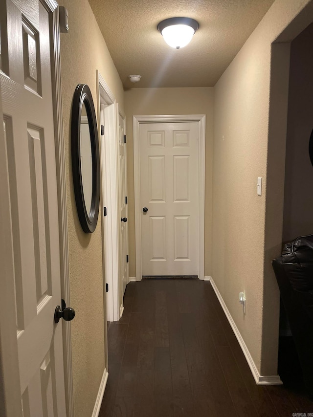 hallway featuring dark wood-type flooring and a textured ceiling