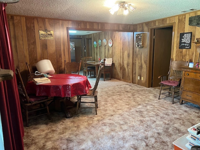 dining space featuring ceiling fan, wood walls, carpet flooring, and a textured ceiling