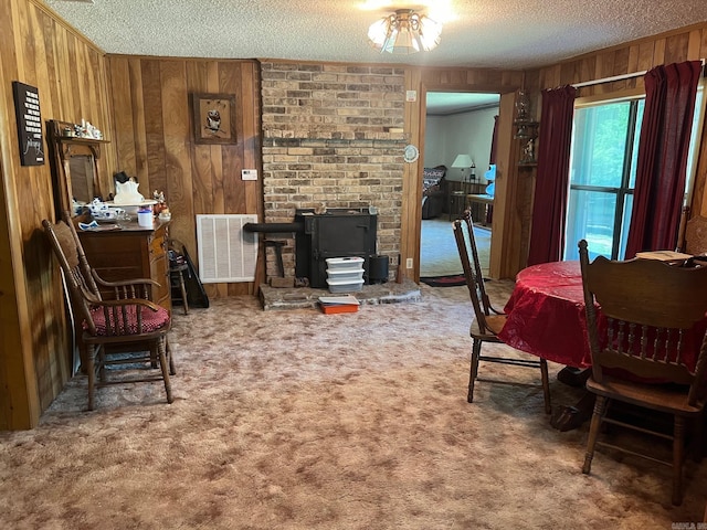 living area with wood walls, a textured ceiling, and carpet