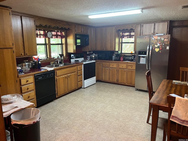 kitchen featuring sink, a textured ceiling, black appliances, and a wealth of natural light