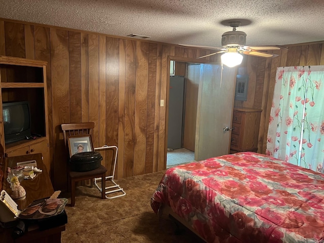 bedroom with ceiling fan, light carpet, a textured ceiling, and wooden walls