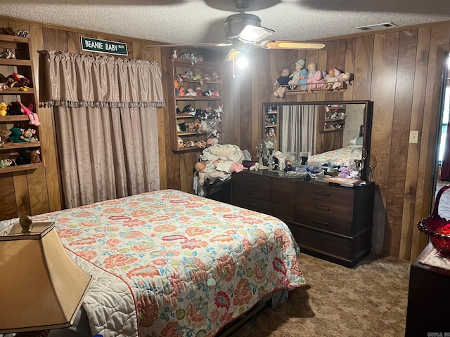 bedroom with ceiling fan, a textured ceiling, carpet floors, and wooden walls