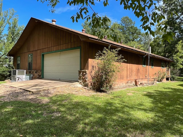 view of side of property featuring central air condition unit, a lawn, and a garage