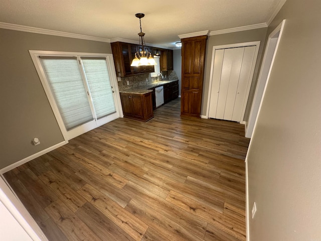 kitchen with wood-type flooring, dishwasher, ornamental molding, pendant lighting, and decorative backsplash