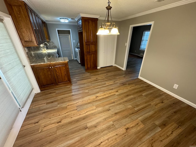 kitchen with a notable chandelier, crown molding, tasteful backsplash, and dark hardwood / wood-style floors