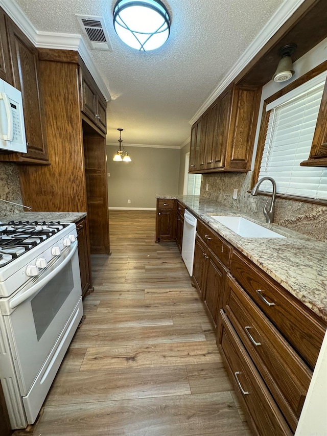 kitchen with tasteful backsplash, light wood-type flooring, sink, decorative light fixtures, and white appliances